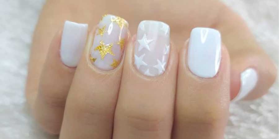 manicura de colores blanco con estrellas doradas con gel de uñas semipermanente